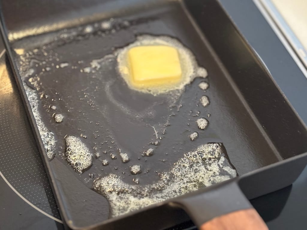 フライパンでバターを熱している調理中の様子
