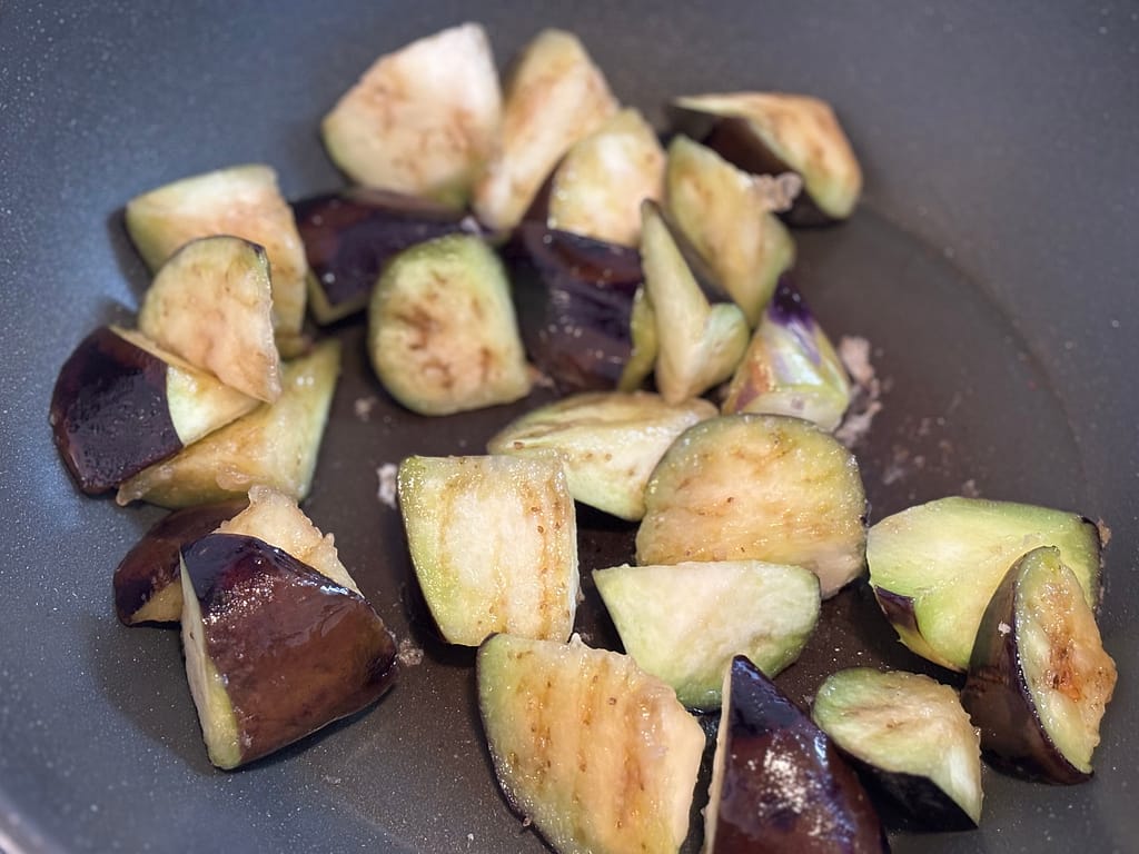 フライパンでナスを炒めているところ。少し油を吸ってしんなりし始めている。