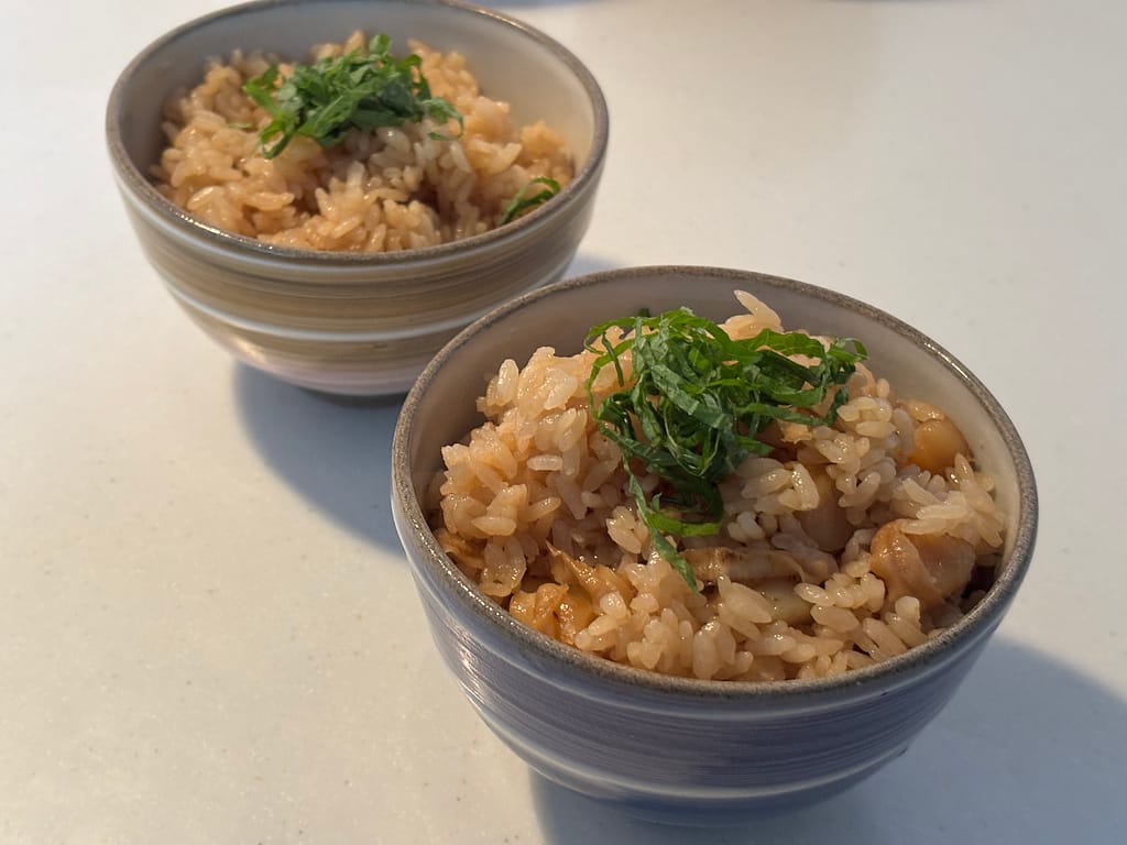 バーミキュラライスポットで炊き上げた北海道産ホタテの炊き込みご飯。青じそを添えた器盛り。