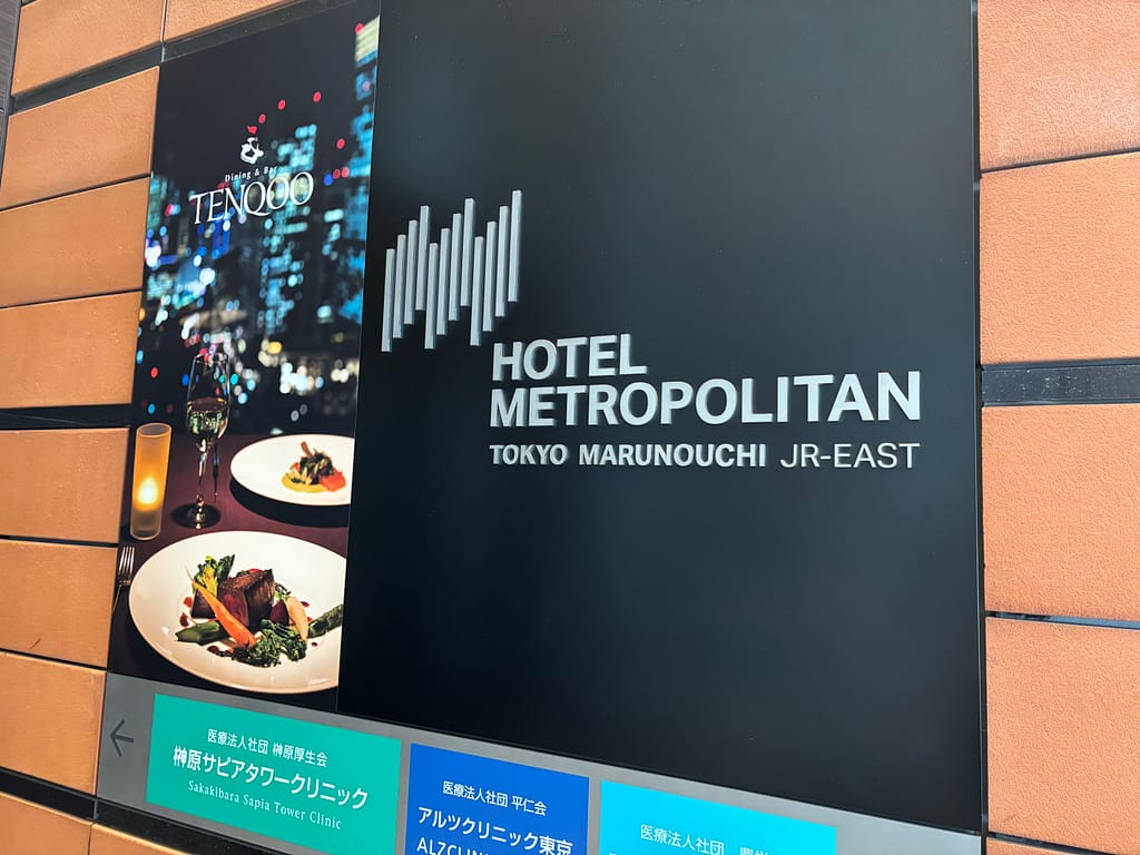 ホテル外観サイン「ホテルメトロポリタン丸の内とダイニング＆バー『TENQOO』の案内看板。東京の夜景とフレンチ料理の写真付き。」