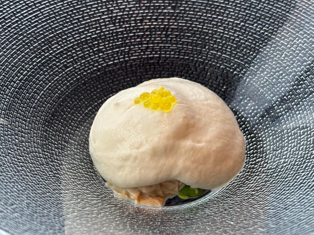 フォアグラの茶碗蒸し風「TENQOOの前菜、フォアグラを使った茶碗蒸し風の料理。クリーミーな泡の上に黄色い粒状ソースが添えられている。」