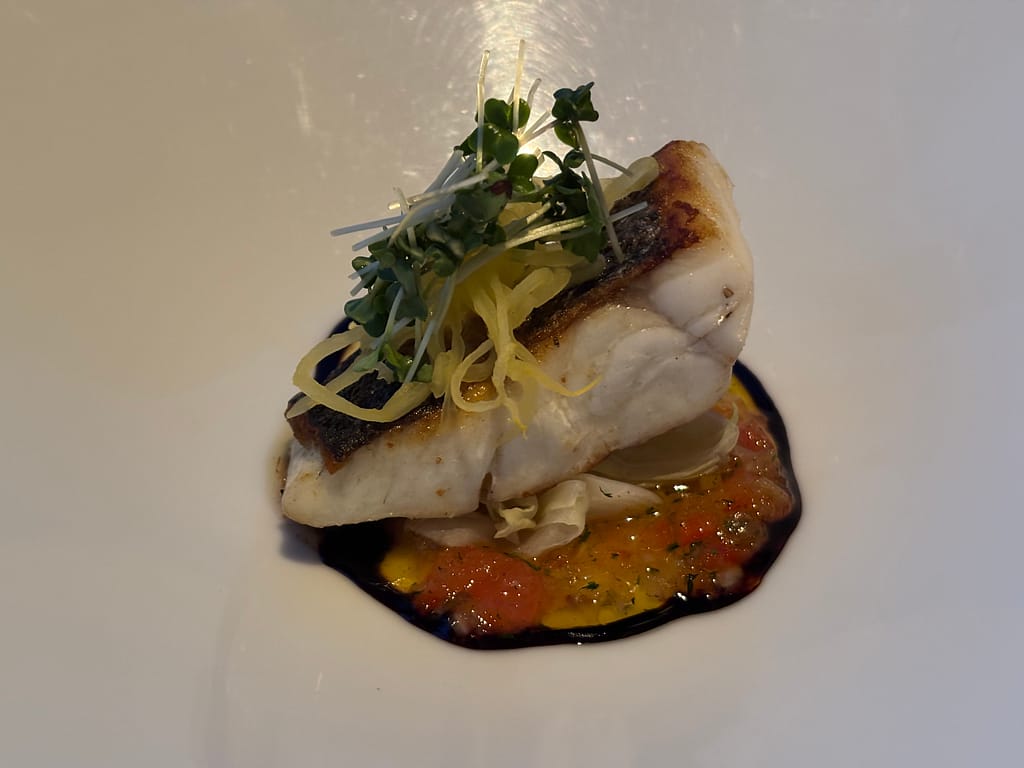 本日の魚料理「皮目を香ばしく焼いた白身魚のポワレ。バルサミコソースとトマトのソースを合わせ、細切り野菜とスプラウトを添えている。」