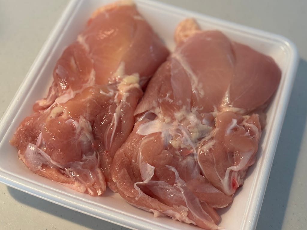 生肉の写真。下処理前の鶏もも肉がパックに入っている様子。