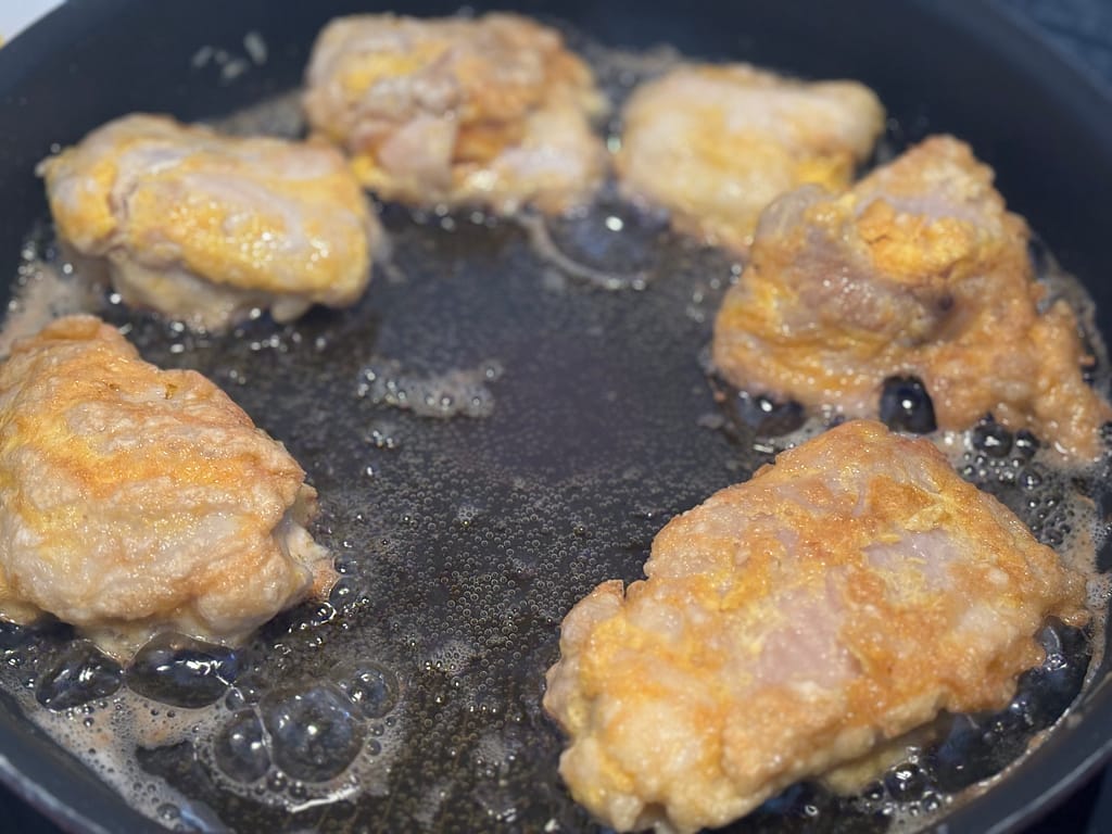 調理中の写真。フライパンで鶏肉を揚げ焼きしている様子。