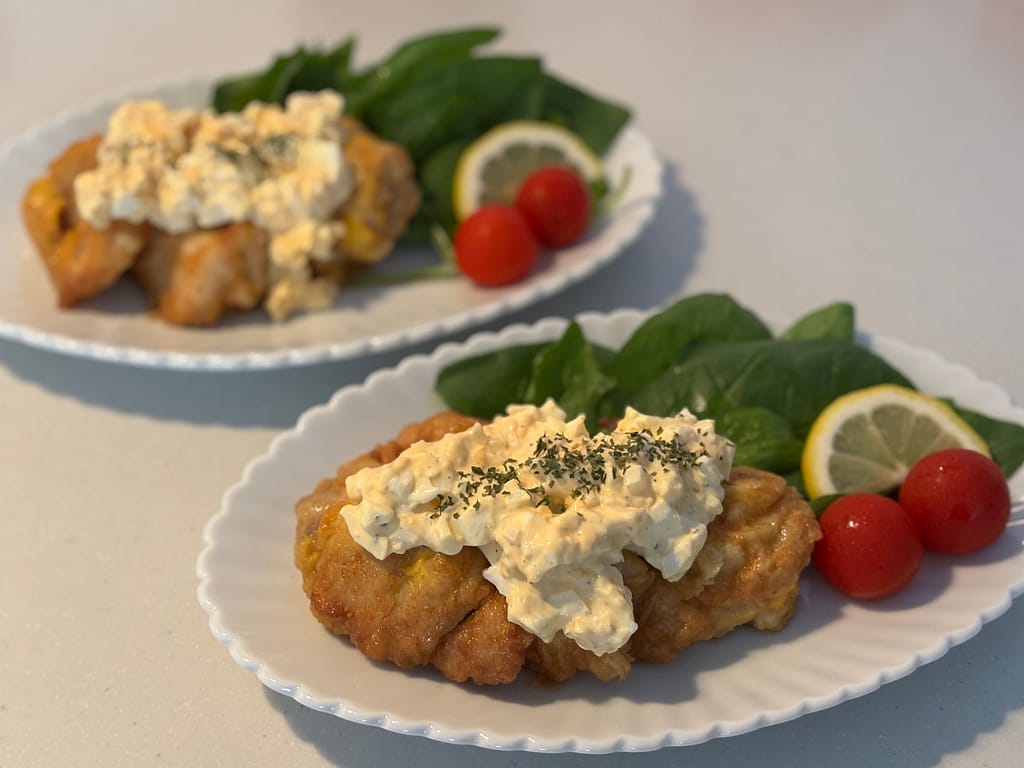 盛り付け写真①タルタルソースをたっぷりかけたチキン南蛮と、レモン・ミニトマト・ほうれん草を添えた完成写真。