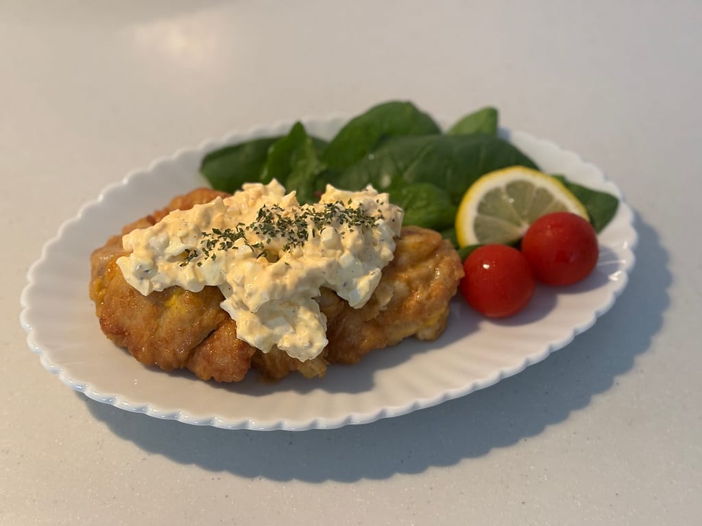 盛り付け写真②タルタルソースをたっぷりかけたチキン南蛮と、レモン・ミニトマト・ほうれん草を添えた完成写真。