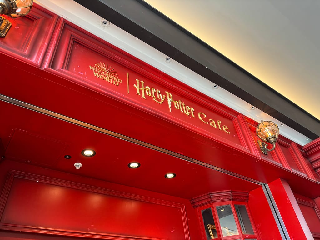 Harry Potter Cafeの入口上部、鮮やかな赤い壁にゴールドのロゴが輝く外観