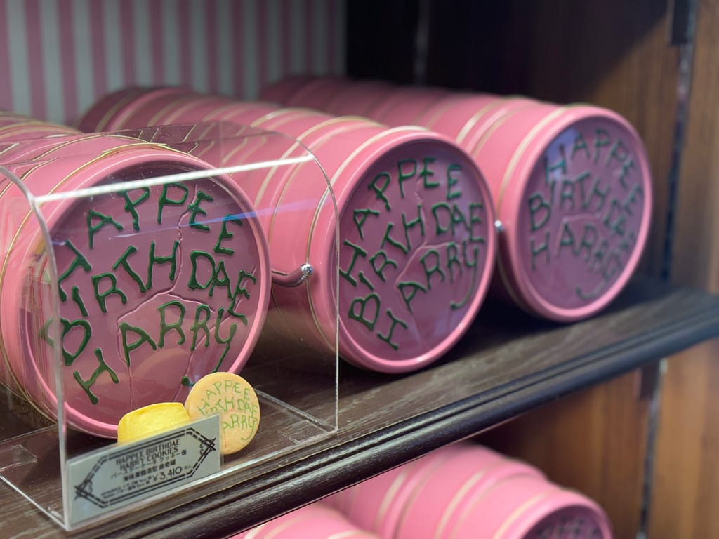 「HAPPEE BIRTHDAE HARRY」クッキー缶、ピンクのパッケージにユニークな文字入り