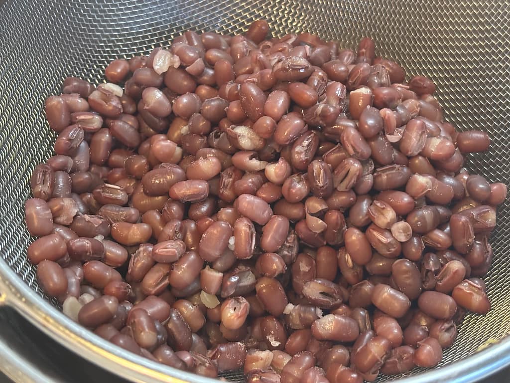 下茹でした小豆を金属製のザルにあけて水気を切っているところ②