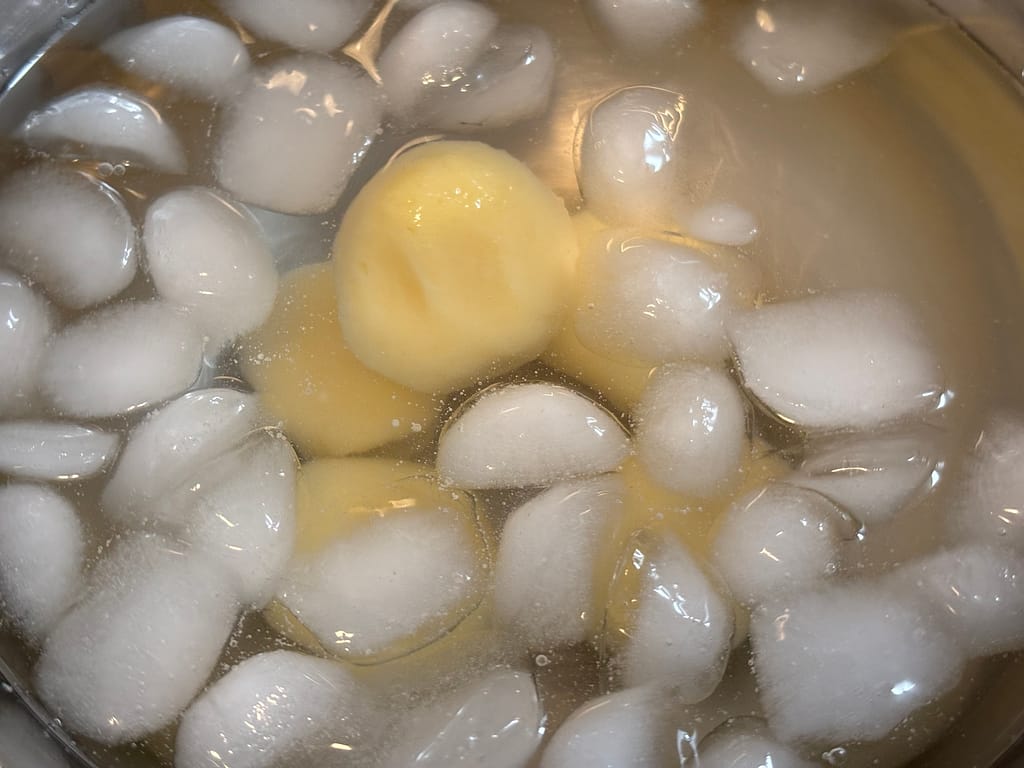 氷水で冷やす団子
茹で上がった団子を氷水に入れて冷ましている様子。白玉が透き通るように浮かび、ツヤが増している。