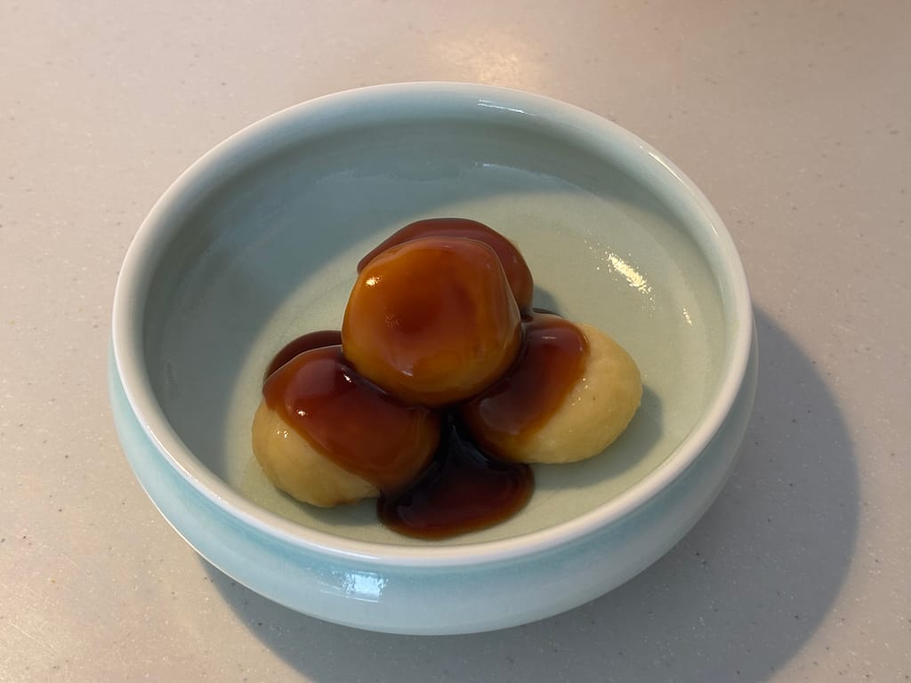 器に盛り付けたみたらし団子
水色の器に3つ並べた団子に、みたらしのタレをたっぷりかけた完成品。艶やかな照りが食欲をそそる。