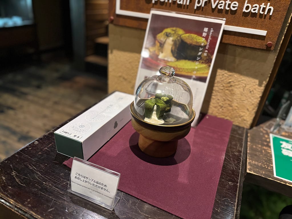 フォンダンショコラの展示(サンプル)吉田屋の嬉野フォンダンショコラ展示サンプル。ガラスドームに入った抹茶色のスイーツがラウンジに飾られている。