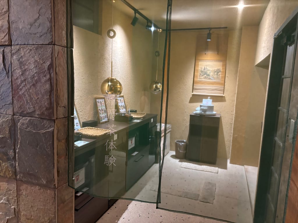 お茶体験コーナー(部屋入口のガラス越し)嬉野温泉 吉田屋のお茶体験コーナー。手もみ茶や煎じ茶体験ができる和の空間で、落ち着いた照明が印象的。