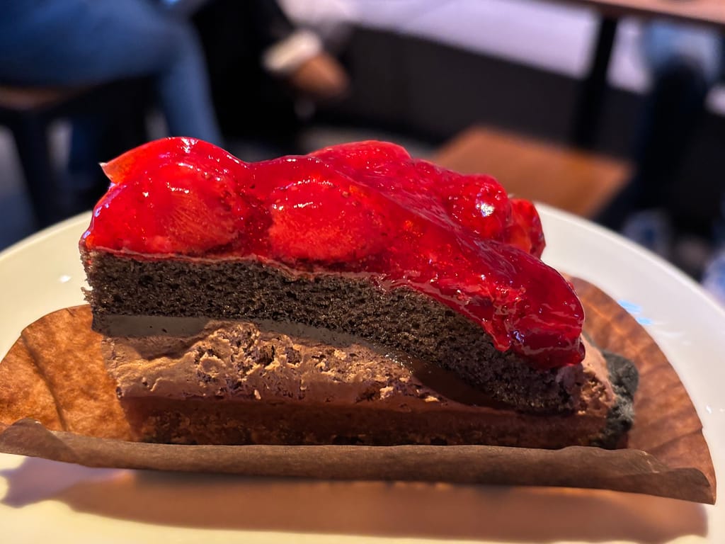 ストロベリー＆チョコレートタルトの断面アップ写真。チョコレートムースと生地の層に、ストロベリーソースが重なる。ストロベリーソースが輝いている。